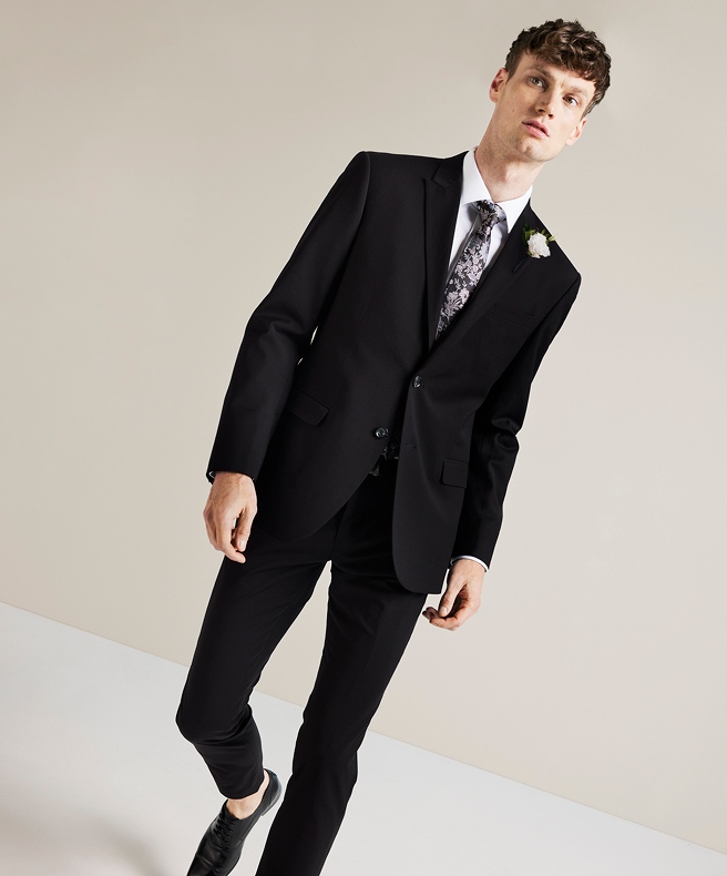 Find Your Fit Model wearing black POLITIX regular fit suit, white shirt and paisley tie standing in front of a white background