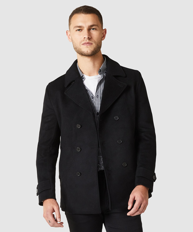 Outfit featuring understated monochrome look Model wearing POLITIX checkered long sleeve shirt with black coat