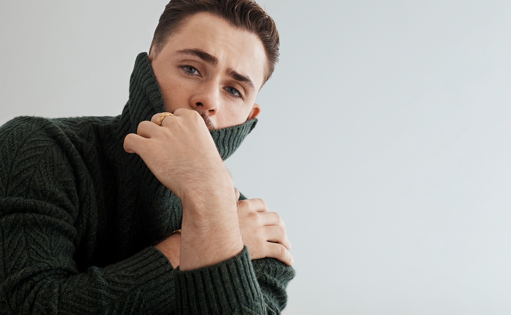 A Knitwear Revival - Top Five Knits of the Season Image of Dacre Montgomery wearing cable knit dark green knit with the neck covering his chin