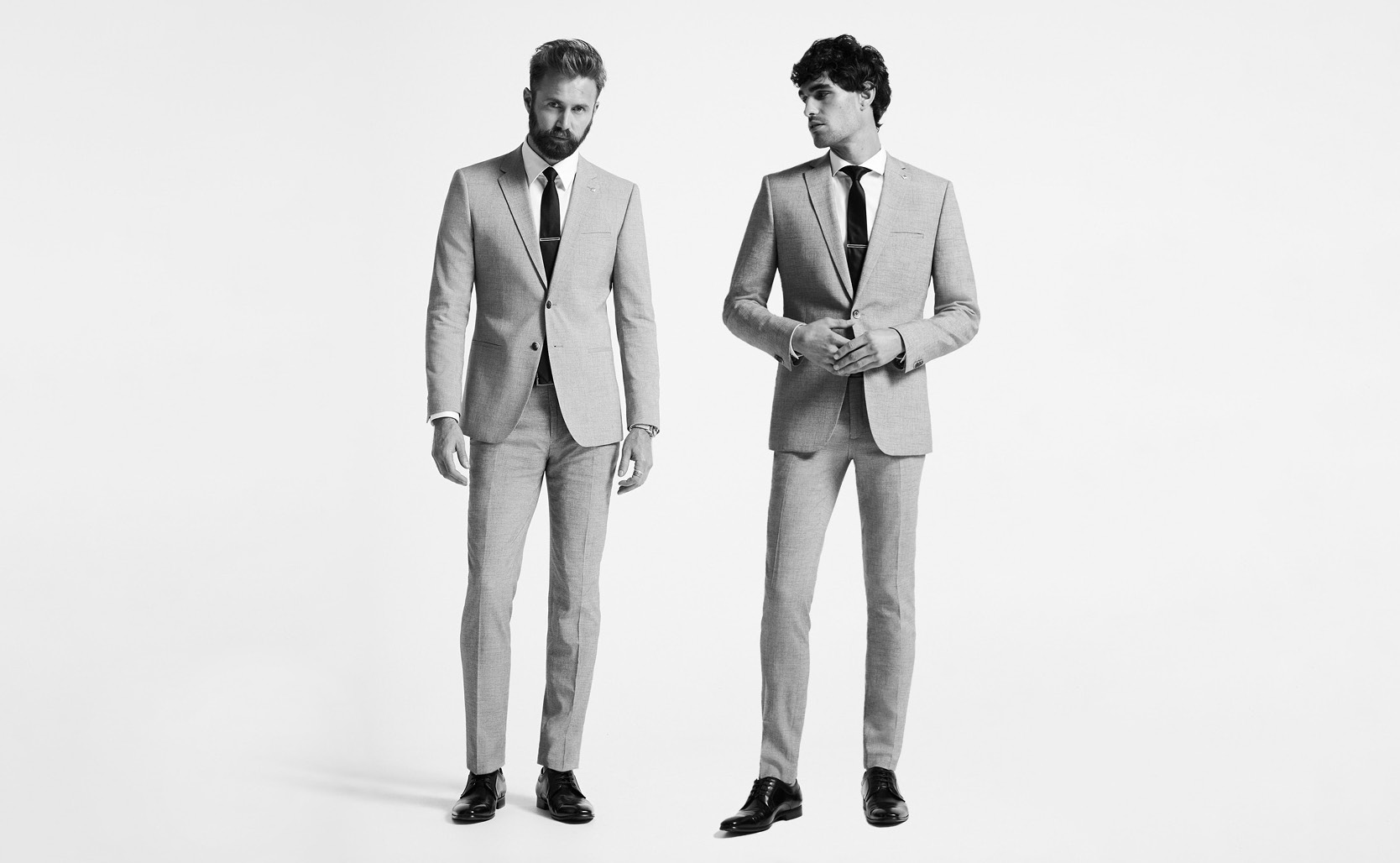 Our best-selling suit, now in more fits. Black and white image of two models wearing the Stretch Marle Tailored Suit in both the Ultra Slim and Regular fit