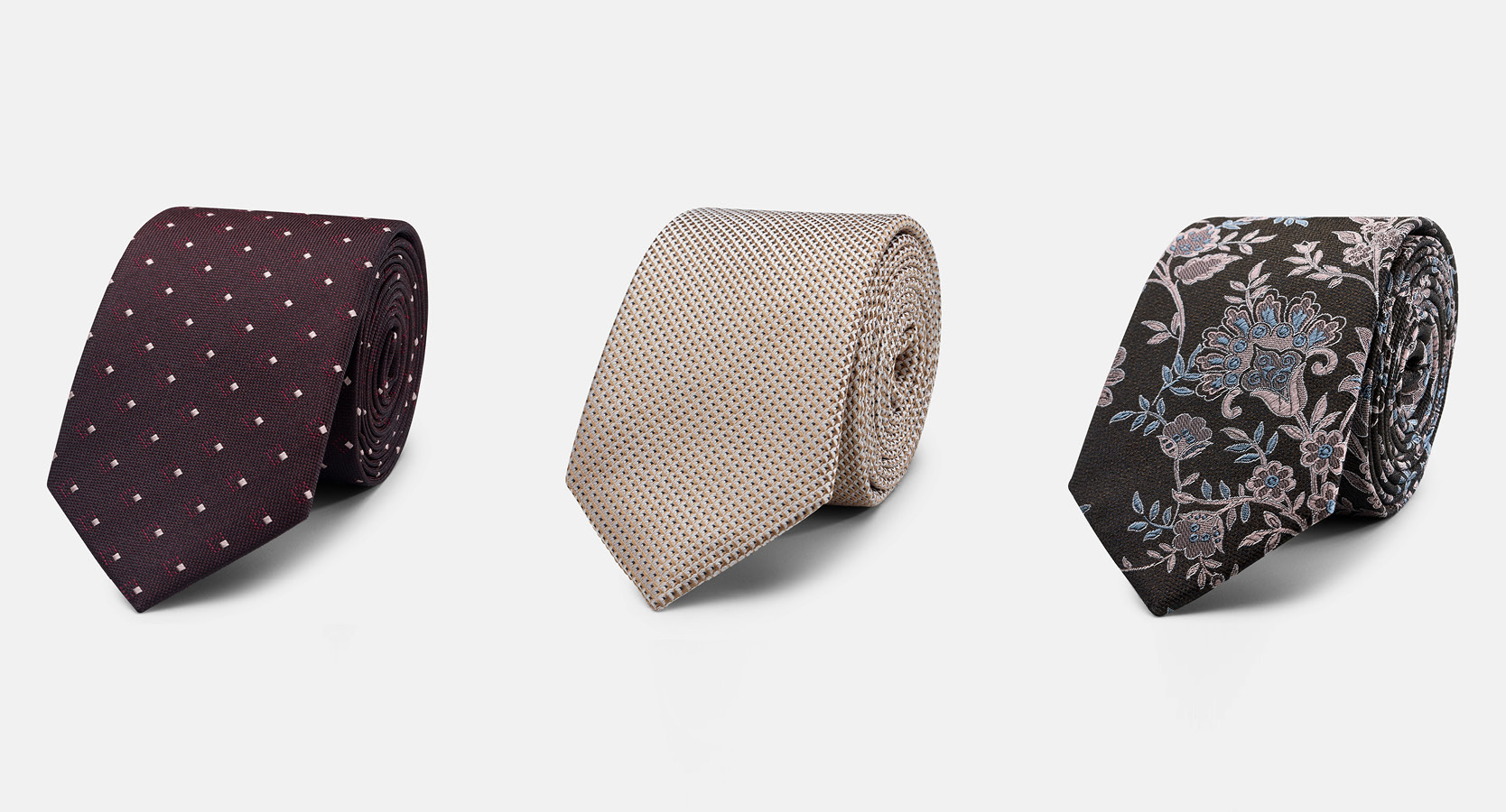 Flat lay of burgundy spotted tie, cream tie and floral tie