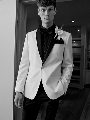 Groom wearing black tie wedding suit pants, black, and white tuxedo jacket.