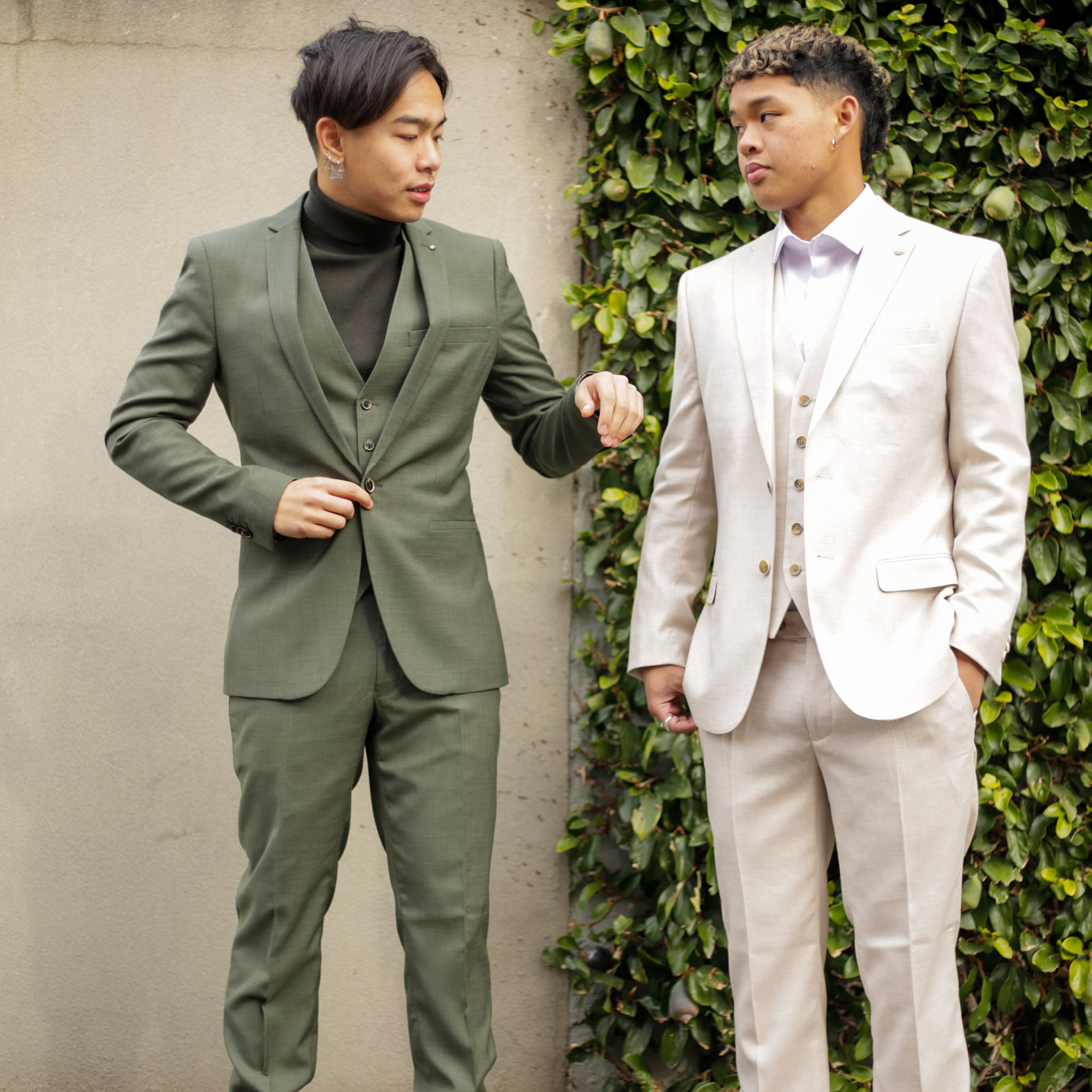 Gnomeboys featuring POLITIX Gnome boys Mike wearing cream POLITIX suit and Nathan wearing dark green POLITIX suit standing in front of a concrete and leafy background